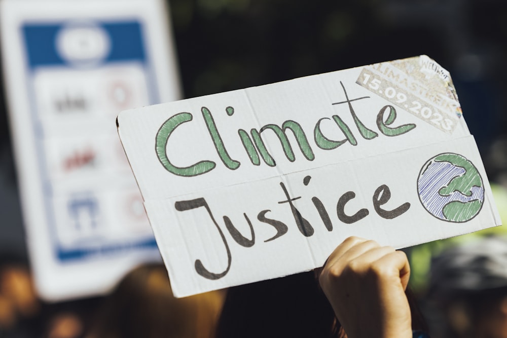 a person holding a sign that says climate justice