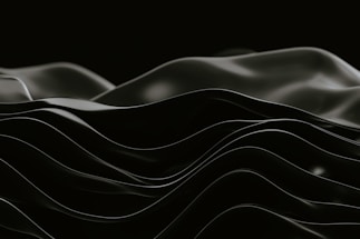 Smooth, undulating black waves create an abstract, minimalist aesthetic against a dark background.