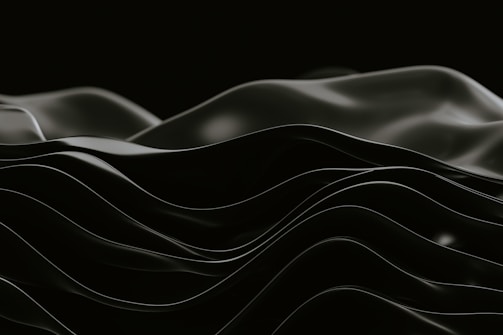 Smooth, undulating black waves create an abstract, minimalist aesthetic against a dark background.