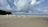 Large letters spelling out 'RELAX' are positioned on a sandy beach with waves in the background. The sky is partly cloudy, and there is lush greenery on the left side.
