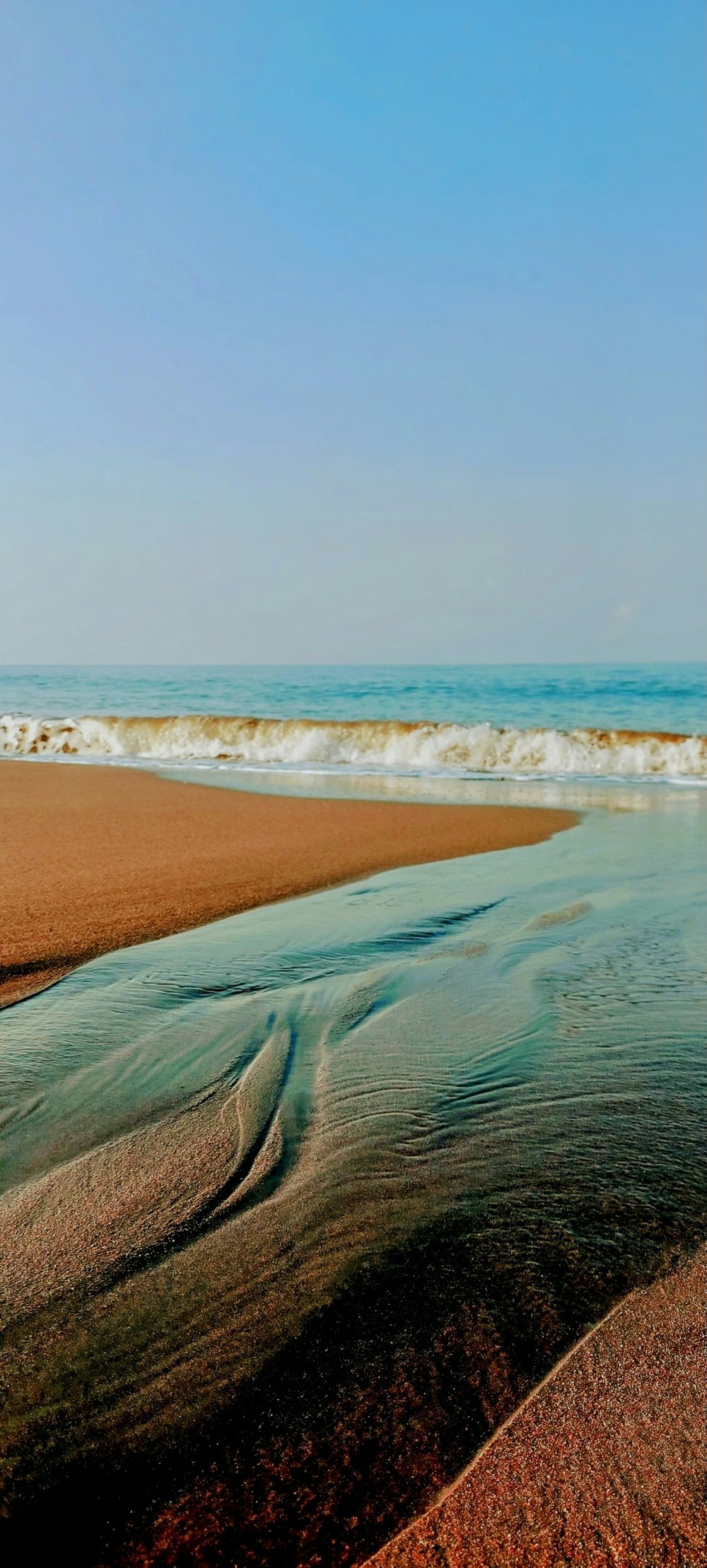 a sandy beach with waves coming in and out of the water