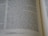 The image features a close-up view of an open book with text in English. The focus is on two main pages with text in a clear, serif font, showing paragraphs and numbered verses.