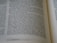 The image features a close-up view of an open book with text in English. The focus is on two main pages with text in a clear, serif font, showing paragraphs and numbered verses.