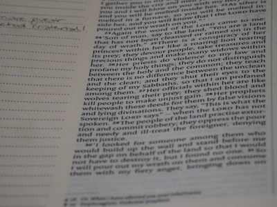 A close-up of hands holding a well-worn Bible with notes and highlights.