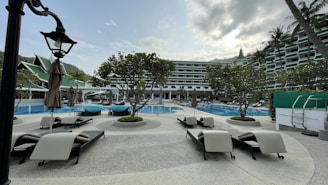 The resort-style swimming pool surrounded by greenery and comfortable lounge chairs.