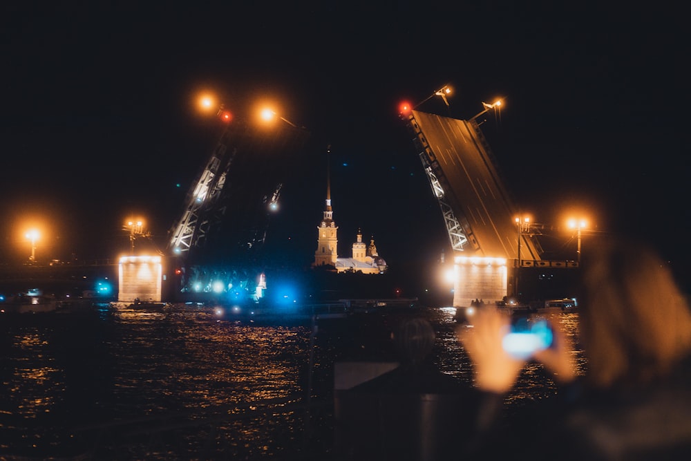 a person taking a picture of a bridge at night