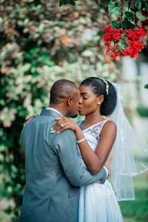 a bride and groom embracing under a tree