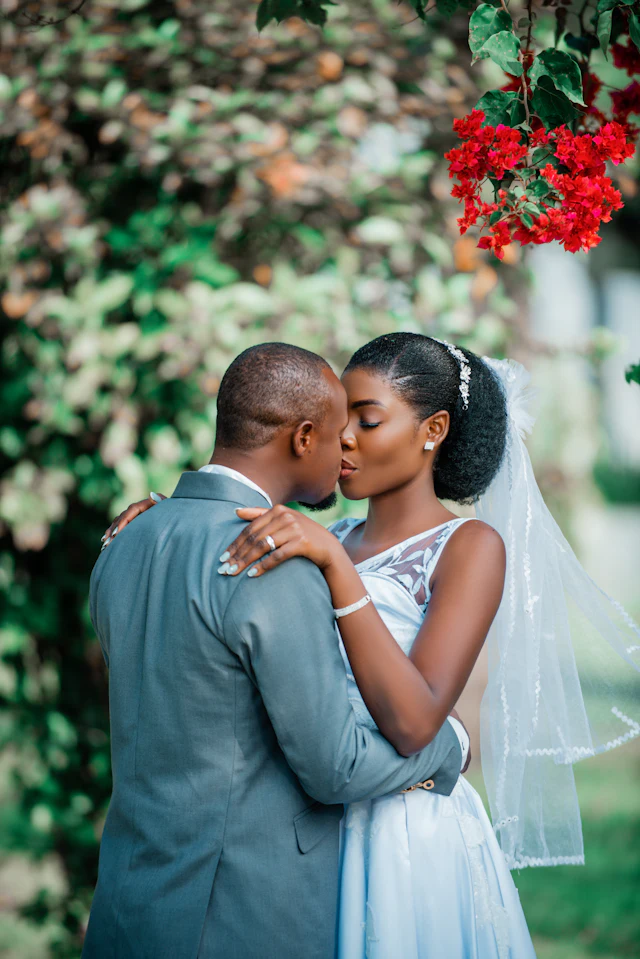 A couple sharing a kiss beneath trees on their wedding day