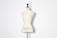 A beige dress form or mannequin torso is placed in front of a plain white background. The top of the mannequin has a black neck and features the inscription 'HAUTE COUTURE STOCKMAN PARIS'. The focus is on the elegant shape and neutral tone of the form.