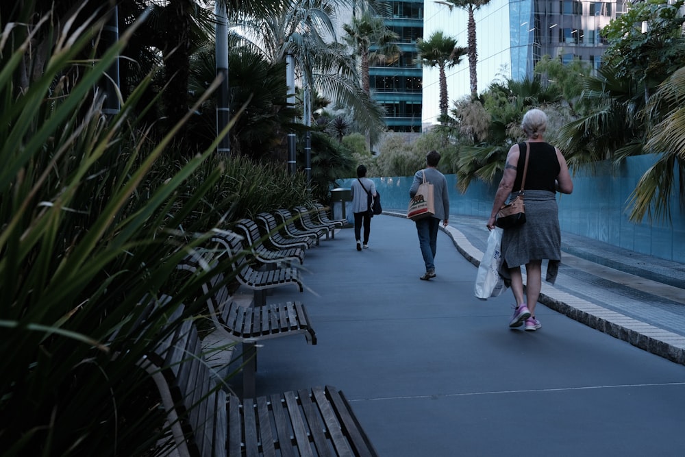 a group of people walking down a sidewalk next to benches