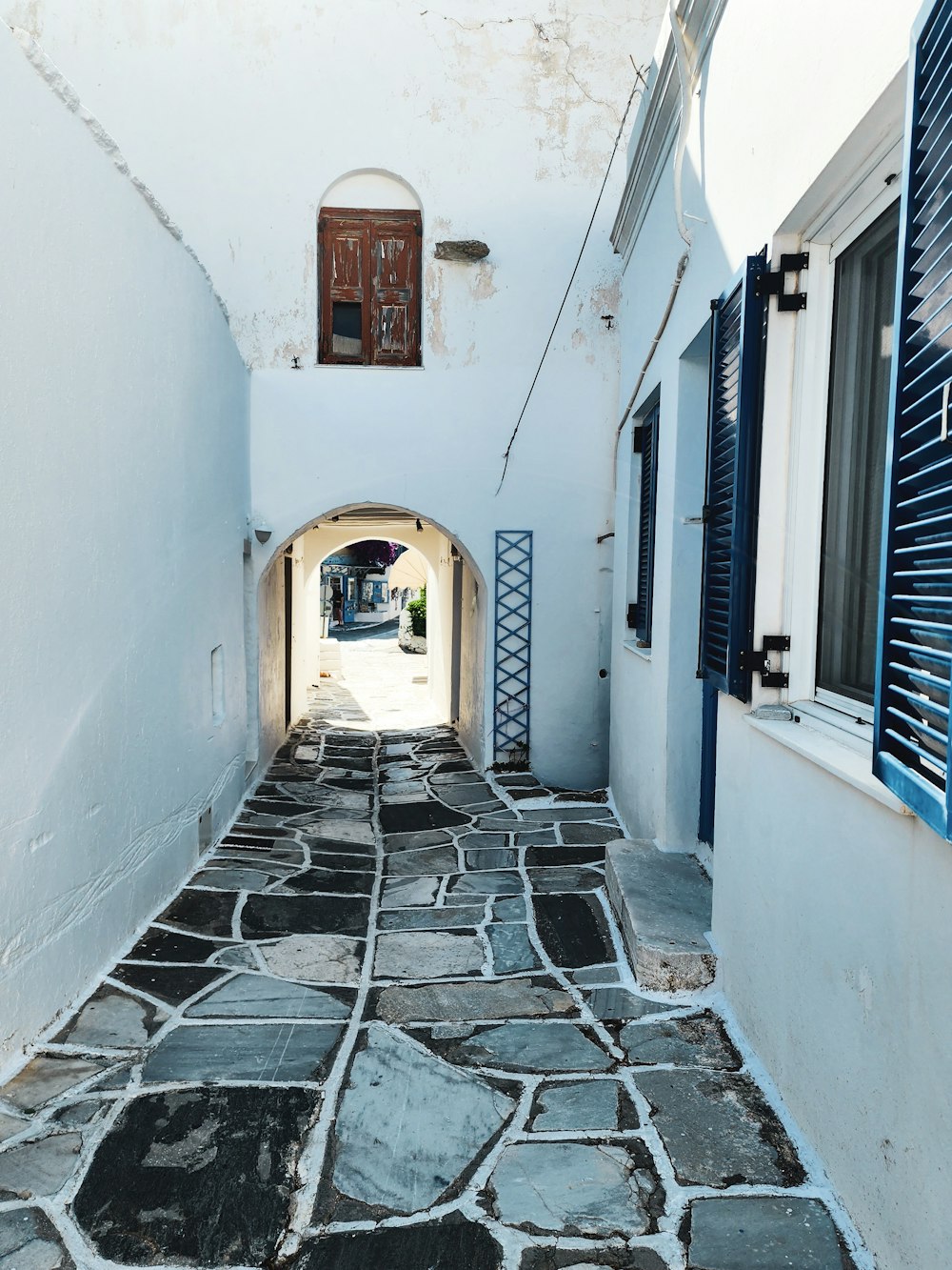 a narrow alley way with blue shutters and windows