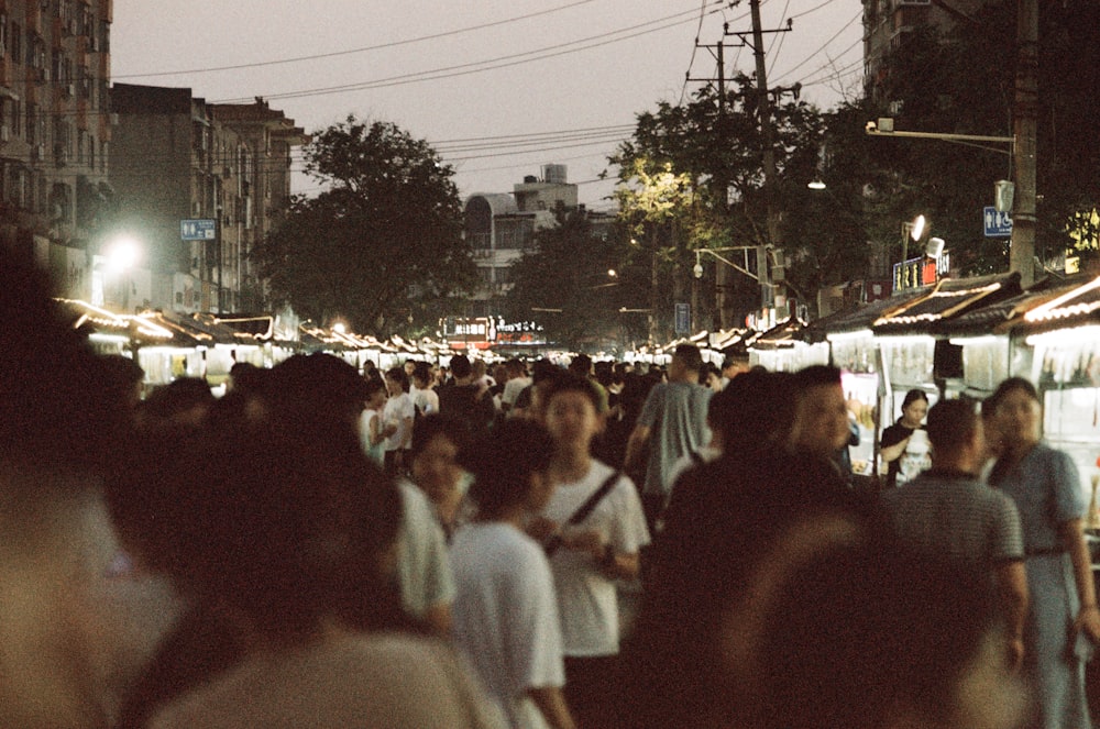 uma multidão de pessoas caminhando por uma rua à noite