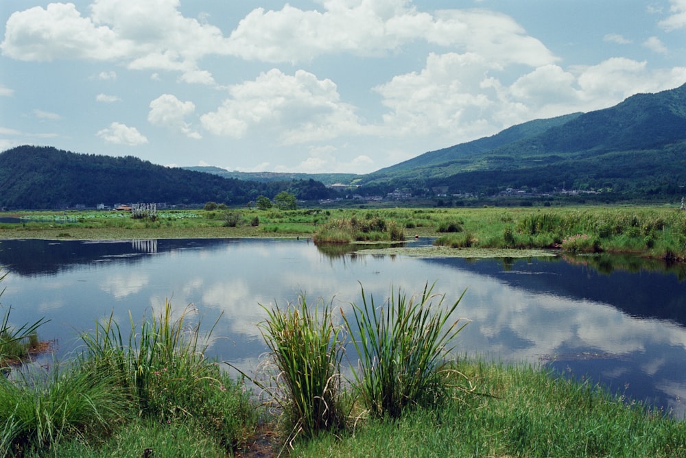 a lake surrounded by lush green mountains under a blue sky