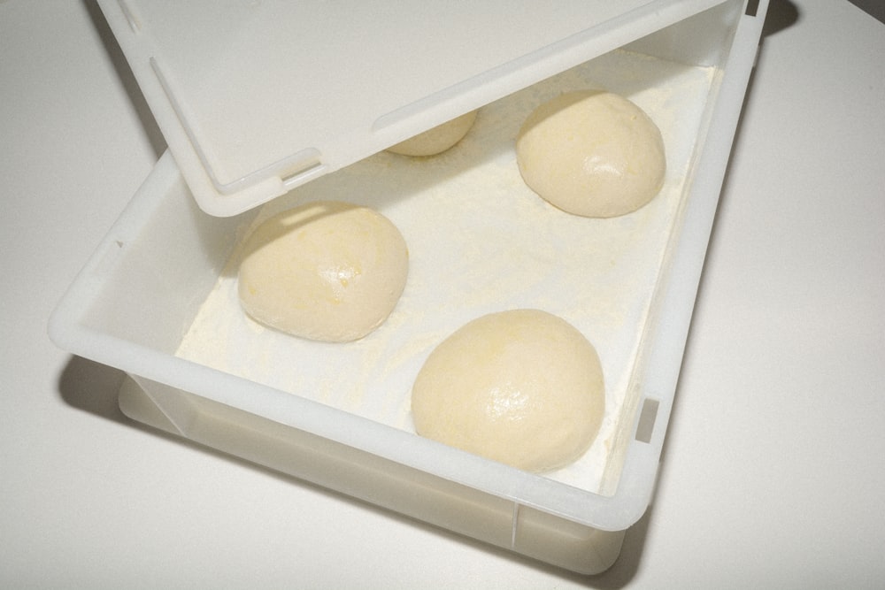 three balls of dough in a plastic container
