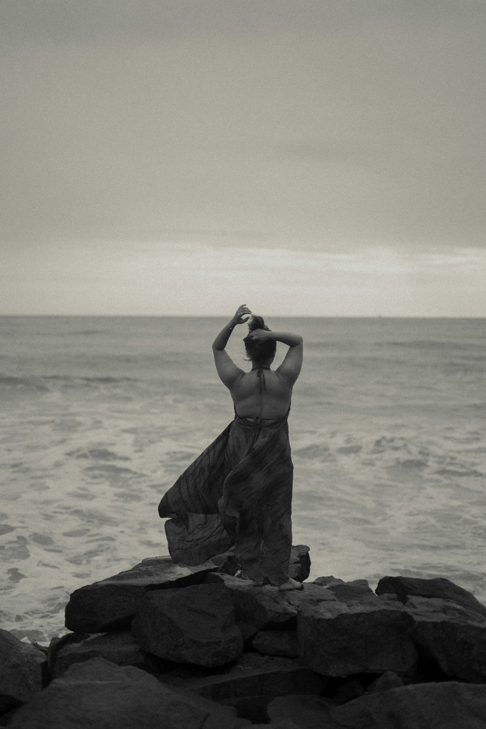 uma mulher em pé em uma rocha perto do oceano
