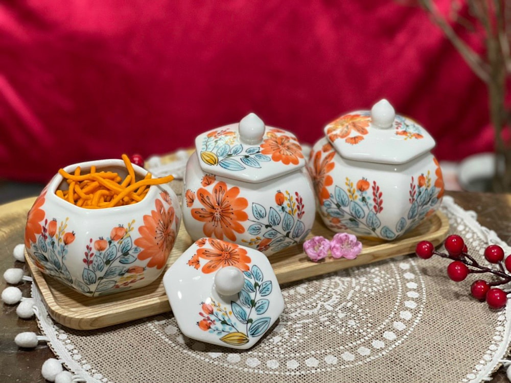 a tray with three teapots and a tray with a bowl of candies