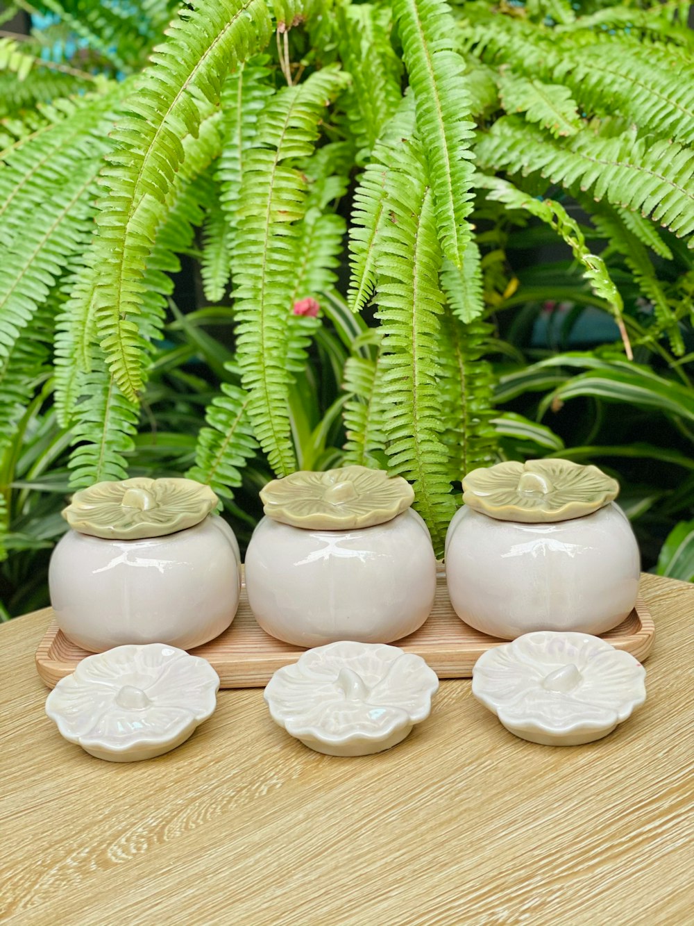 a group of four white vases sitting on top of a wooden table