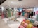 An interior view of a clothing store displaying mannequins dressed in casual outfits. There are racks of colorful clothing in the background and stacks of neatly folded garments in the foreground. The store has a modern and well-lit ambiance.