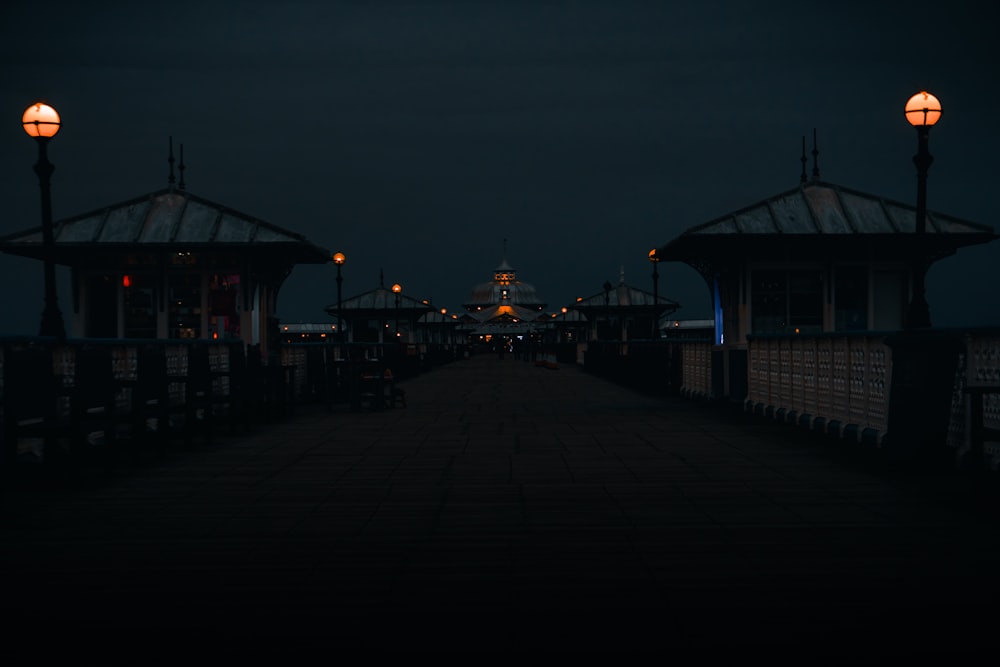 a pier at night with lights on and benches