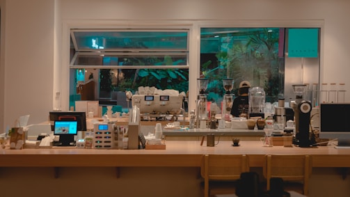 A cozy coffee counter with plants and warm lighting creating a soft ambiance.