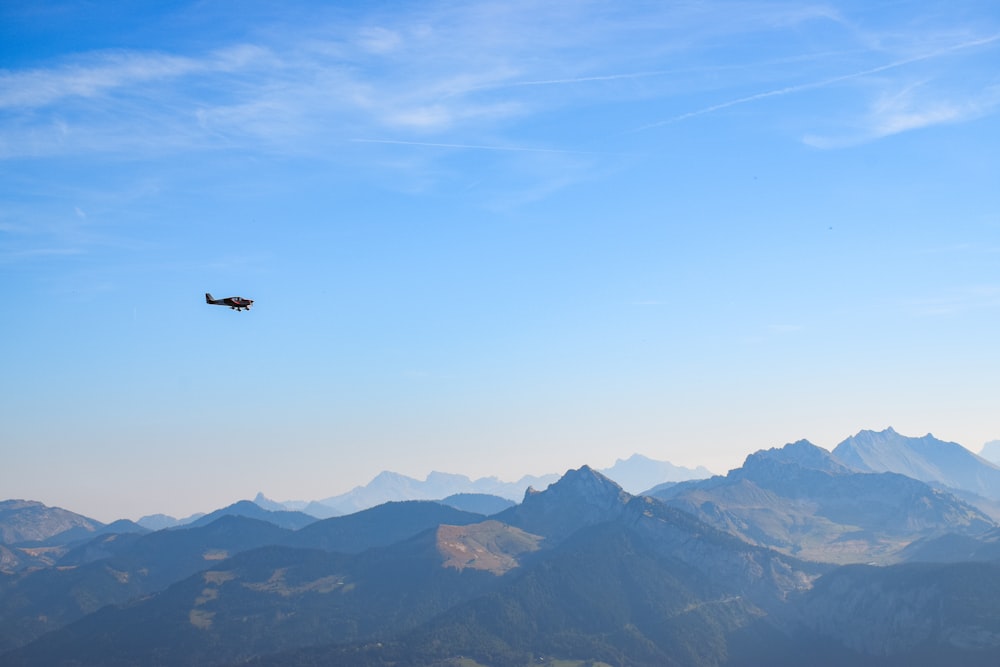 a plane flying over a mountain range with mountains in the background