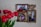 A decorative photo frame with three pictures is displayed on a textured wall. The frame features intricate designs with birds and leaves, and is made of a bronze or gold-colored material. To the left of the frame is a bouquet of bright red tulips with green stems.