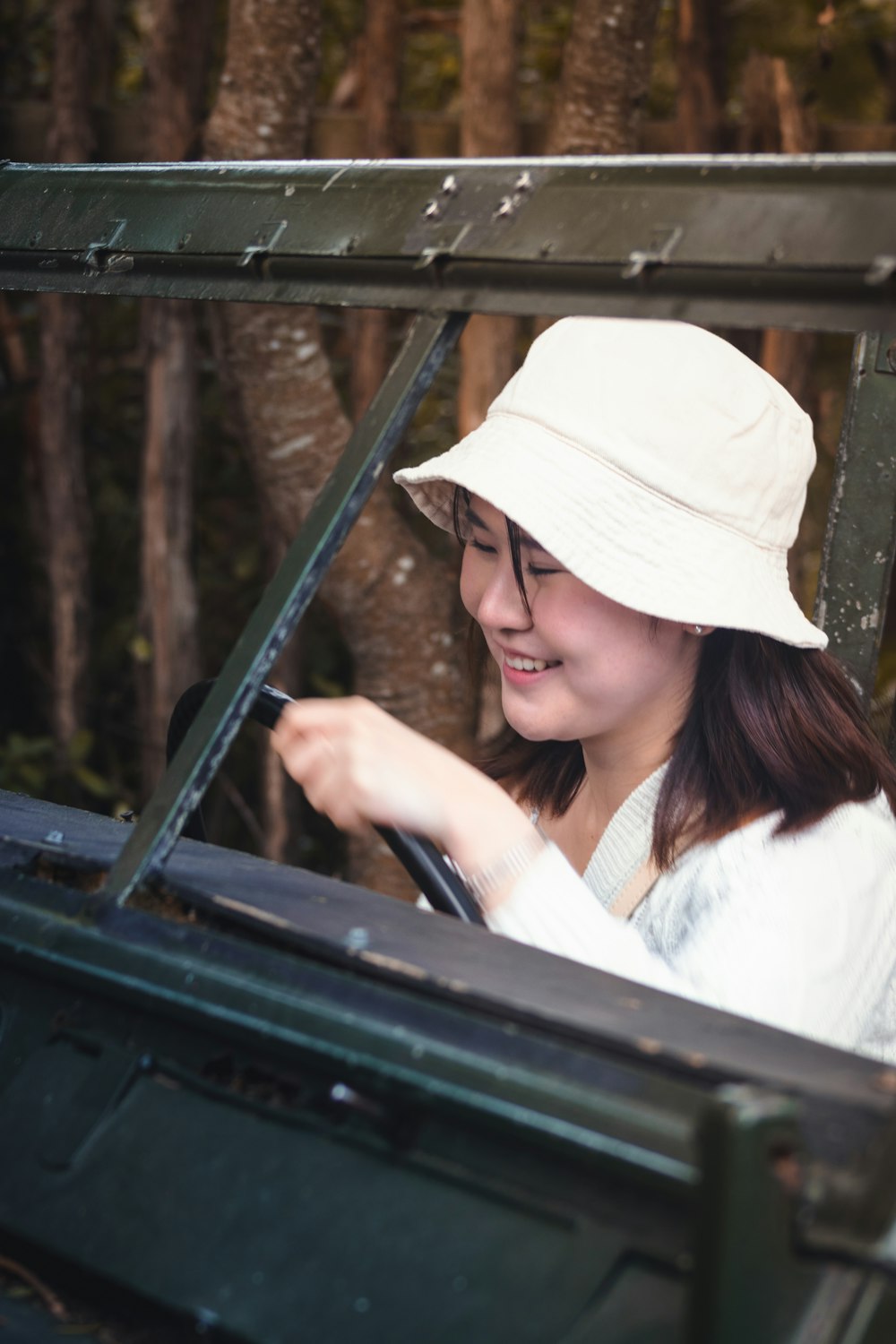 a woman in a white hat driving a green jeep