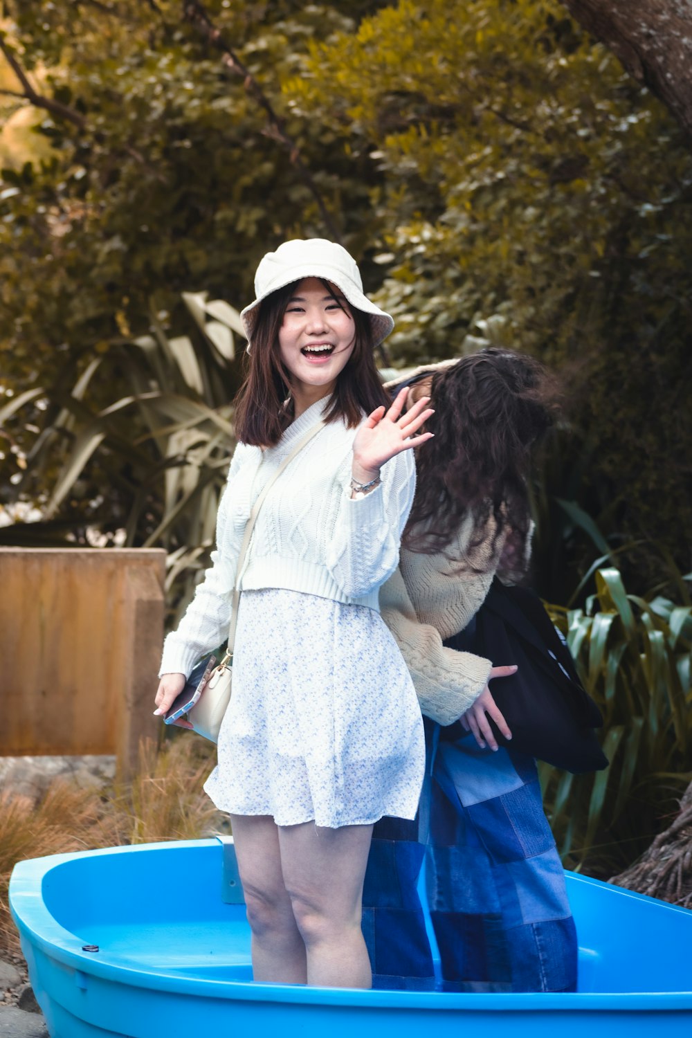 a woman in a white dress and hat standing in a blue pool