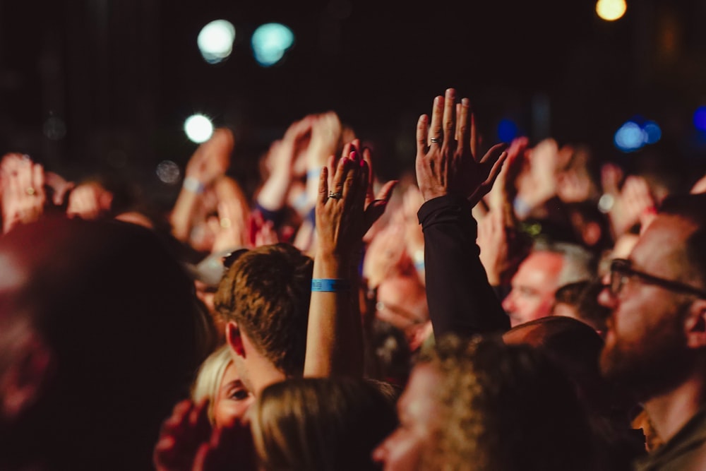 a crowd of people with their hands in the air