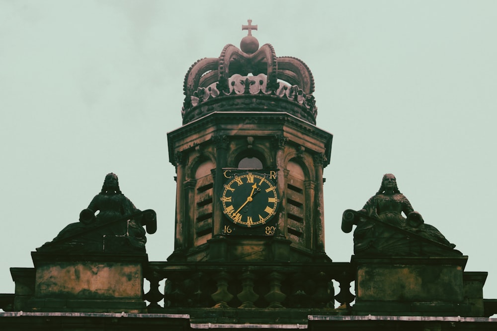 a clock tower with statues on top of it