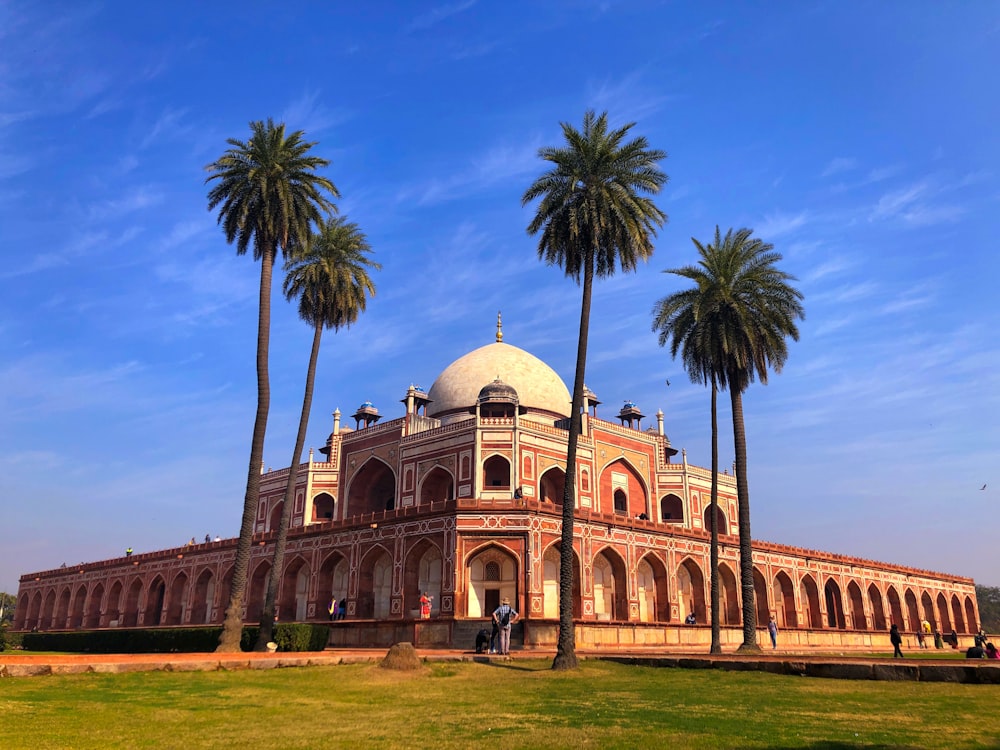 a large building surrounded by palm trees on a sunny day