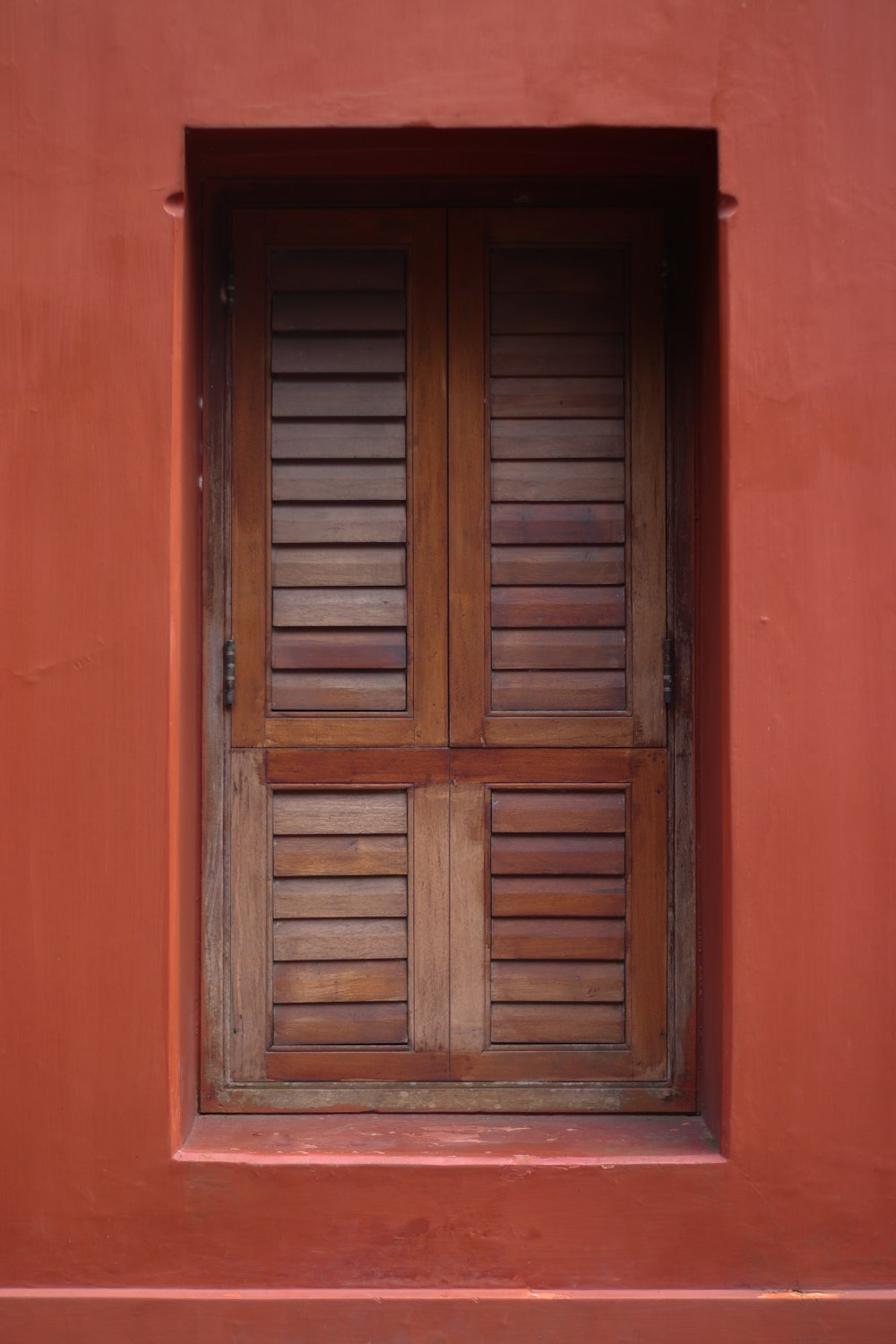 eine rote Wand mit einer Holztür und einem Fenster