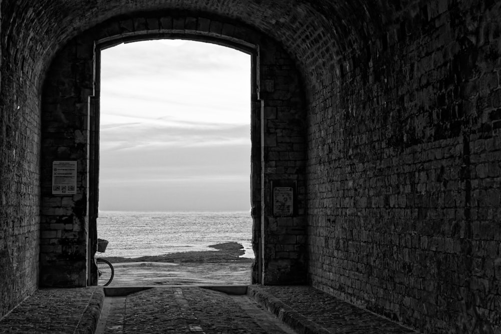 a black and white photo of a door leading to the ocean
