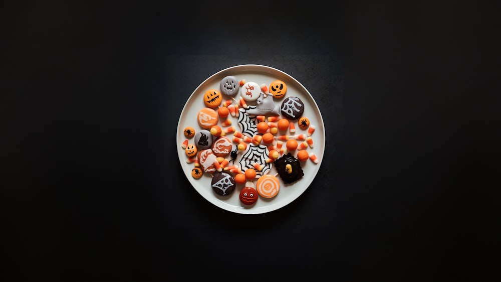 Un plato blanco cubierto con muchos dulces de Halloween