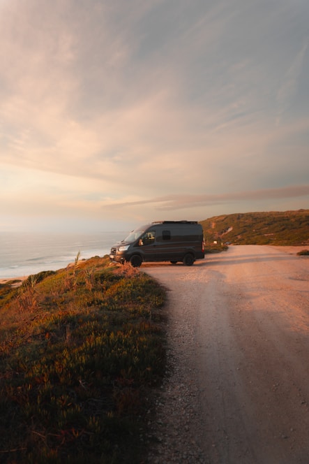 A comfortable shuttle van parked by a scenic coastal road in the Illawarra region at sunset