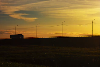 A fleet of modern cargo trucks driving on a highway at sunset, symbolizing reliable logistics