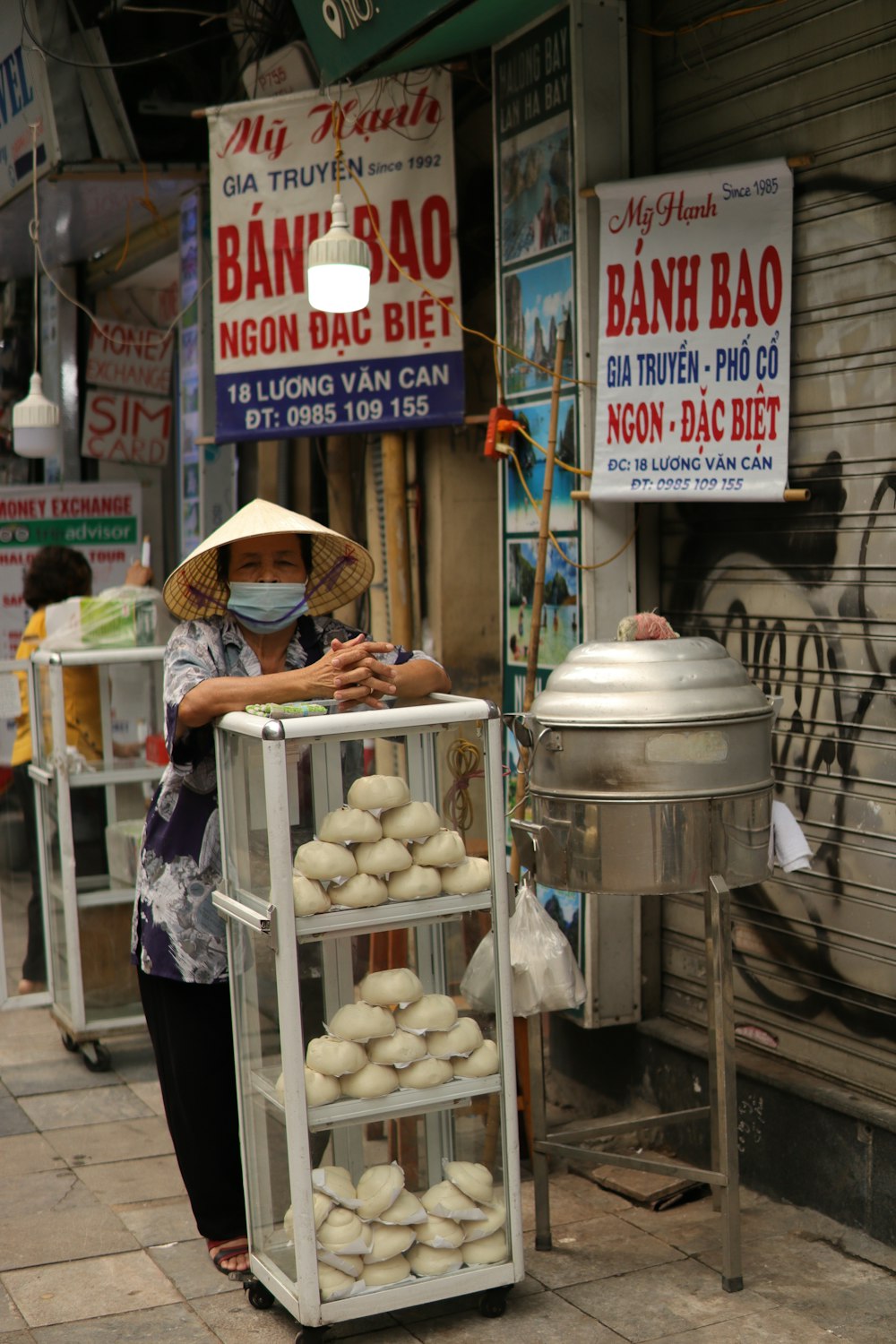 a woman standing next to a cart filled with donuts