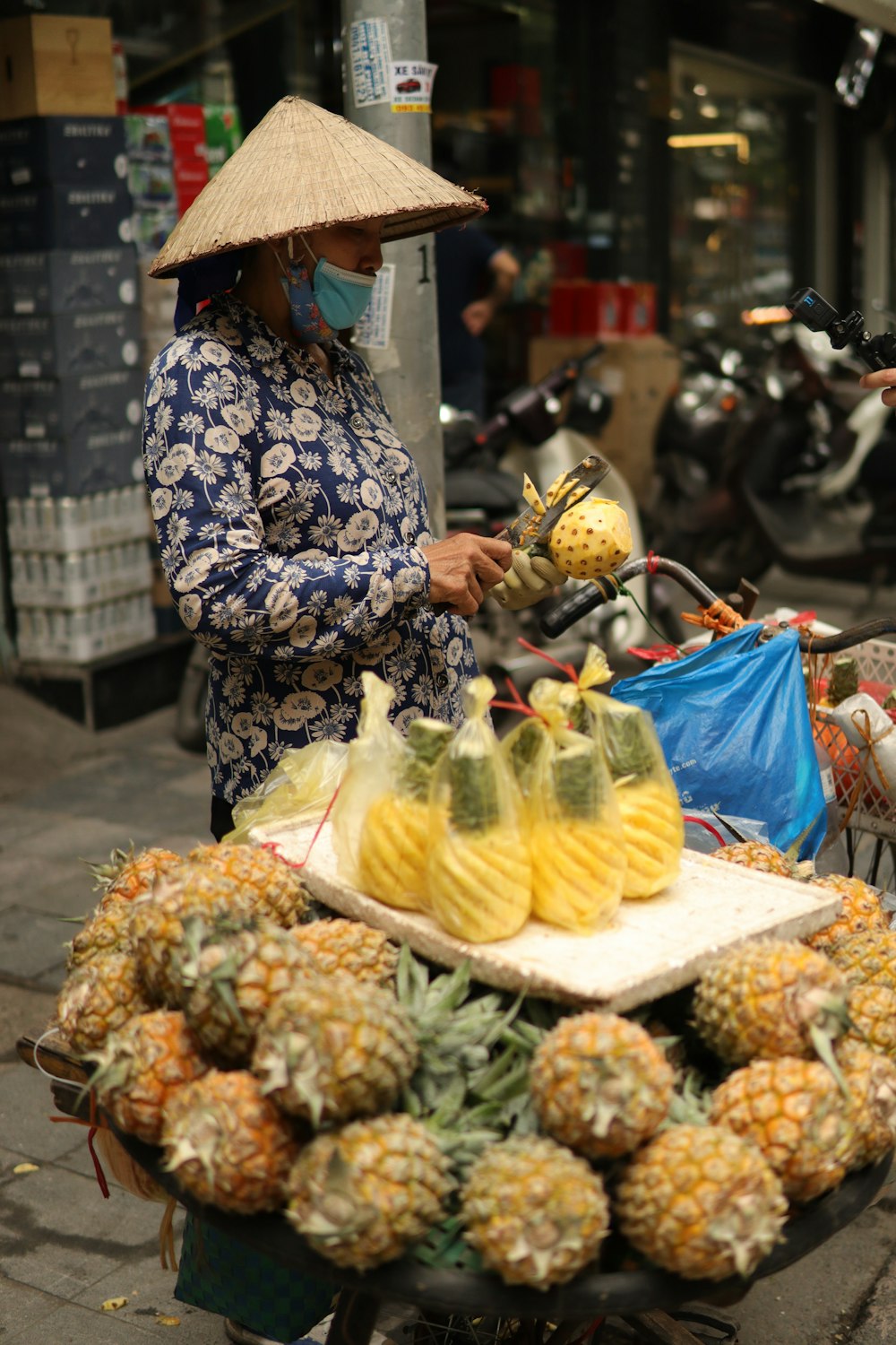a woman in a straw hat is selling pineapples