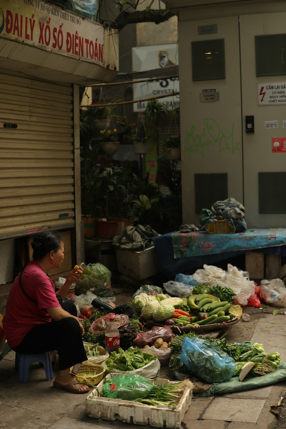 a woman sitting on a bench next to a pile of vegetables