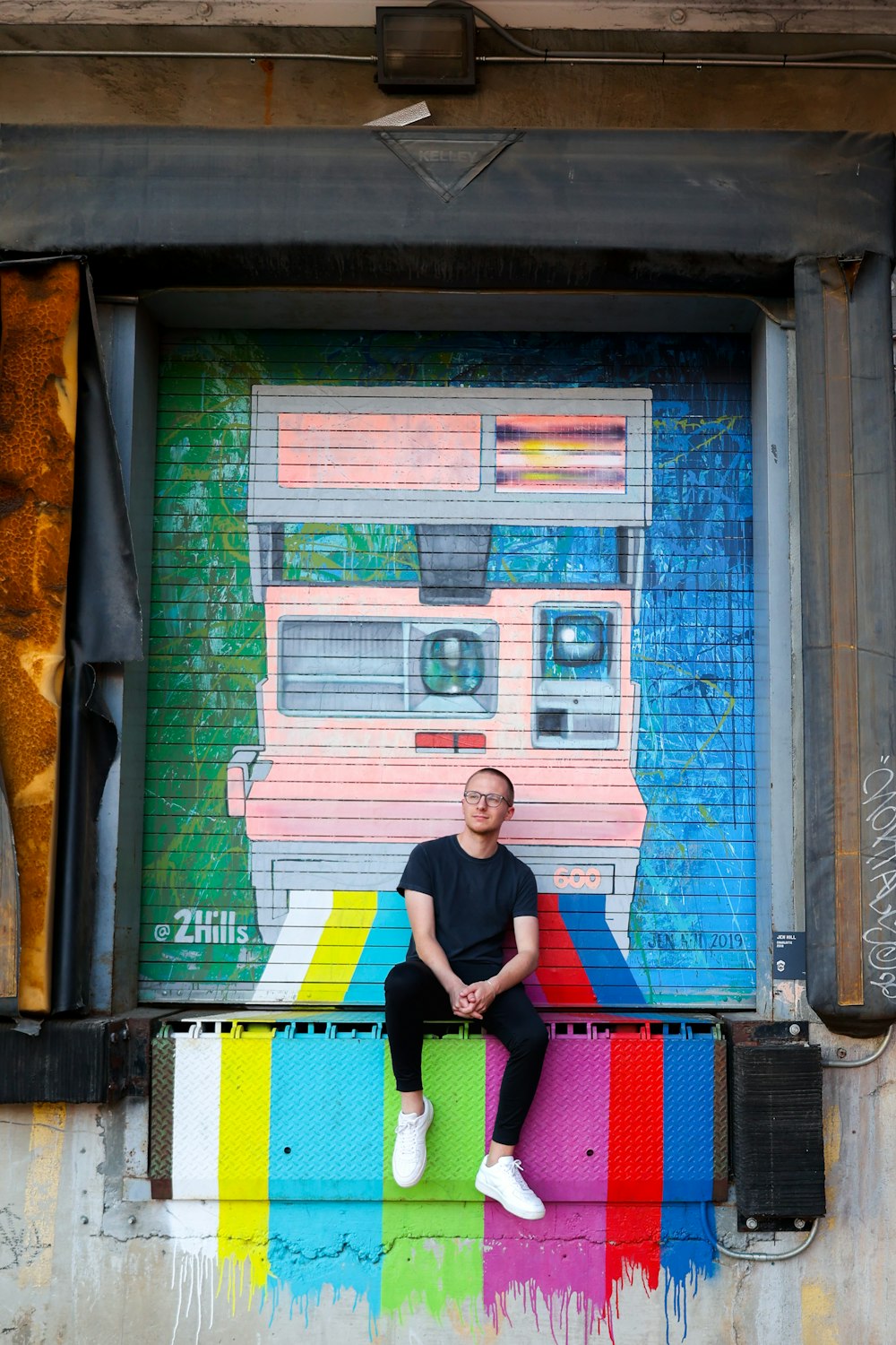 a man sitting on a ledge in front of a colorful wall