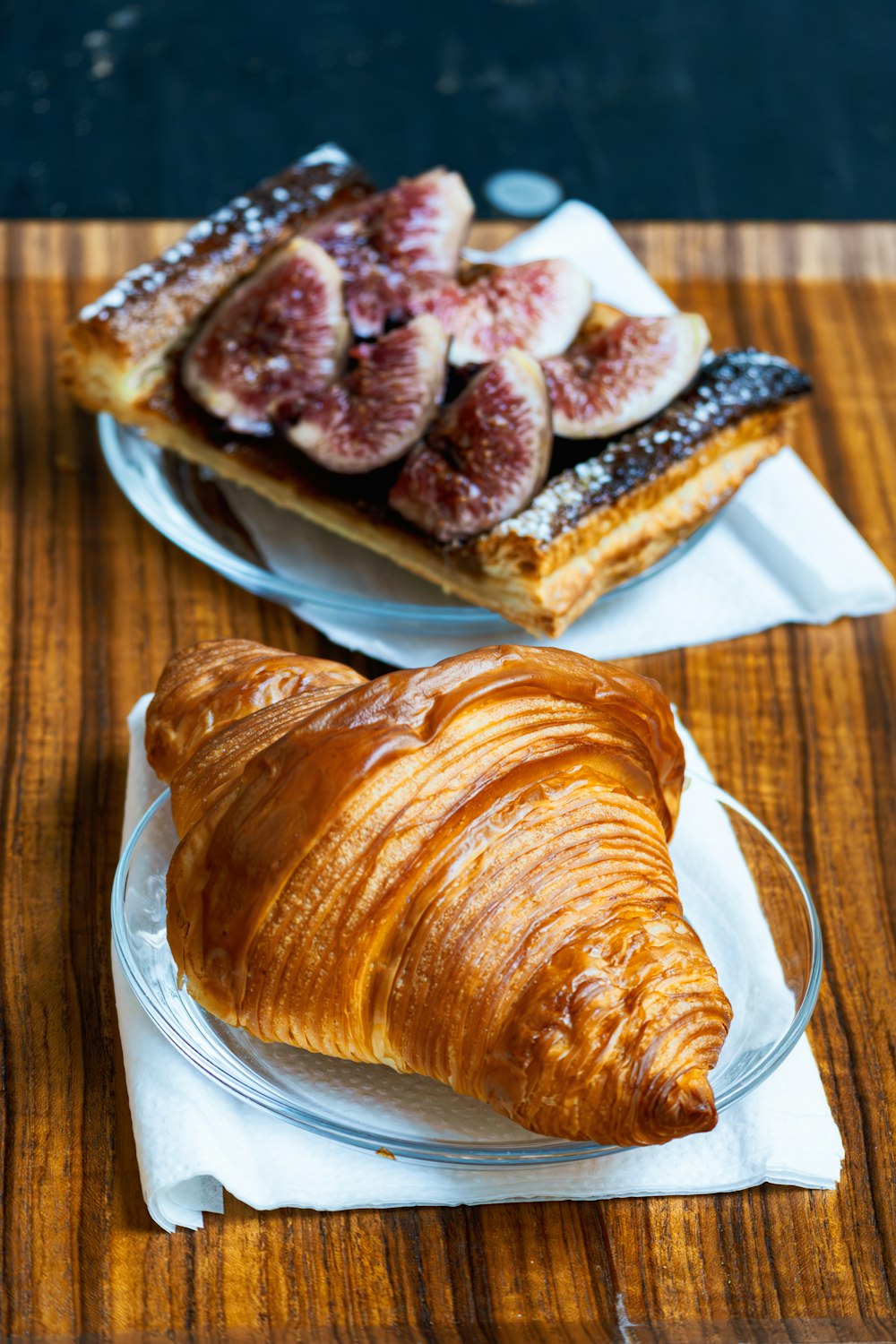 a croissant on a plate next to a pastry on a plate