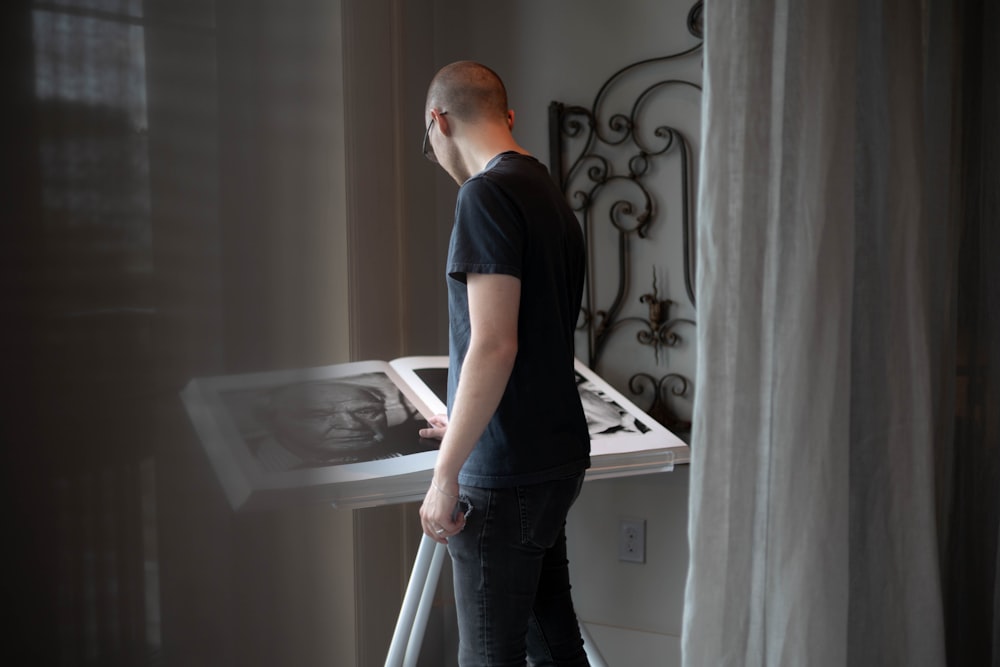a man standing in front of a table with a laptop on it