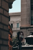A cityscape featuring historic European architecture with ornate details. A partial view of a no entry traffic sign and the corner of a building adds an urban element. Soft lighting casts gentle shadows, enhancing the textures of the stone facades.