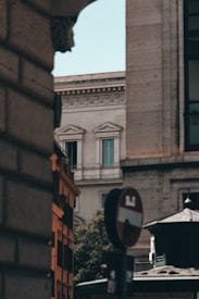 A cityscape featuring historic European architecture with ornate details. A partial view of a no entry traffic sign and the corner of a building adds an urban element. Soft lighting casts gentle shadows, enhancing the textures of the stone facades.