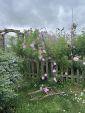 A craftsman carefully installing a wooden garden fence surrounded by blooming flowers.