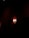 Two wall-mounted lamps with white shades emit a warm glow against a background of deep red, textured drapery. The lighting creates dramatic shadows, enhancing the luxurious ambiance.