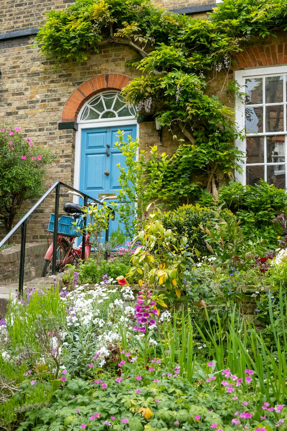 a house with a blue door surrounded by flowers