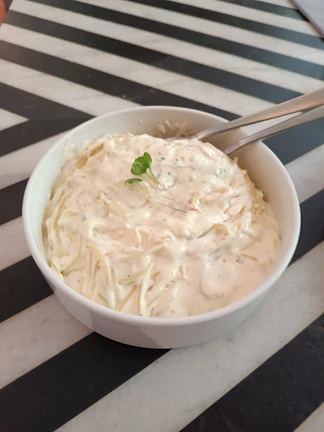 Bright overhead shot of a bowl filled with creamy avocado pasta garnished with cherry tomatoes.