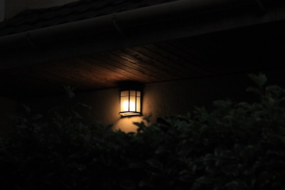 A softly glowing lantern hanging outside a rustic tavern door at twilight.