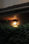 An outdoor wall lantern glowing softly on a porch during twilight.